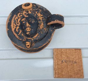 Necropoli. Deposizione n. 614. Guttus a vernice nera con testa di Medusa.Fine del IV sec.a.C.-III sec. a.C.